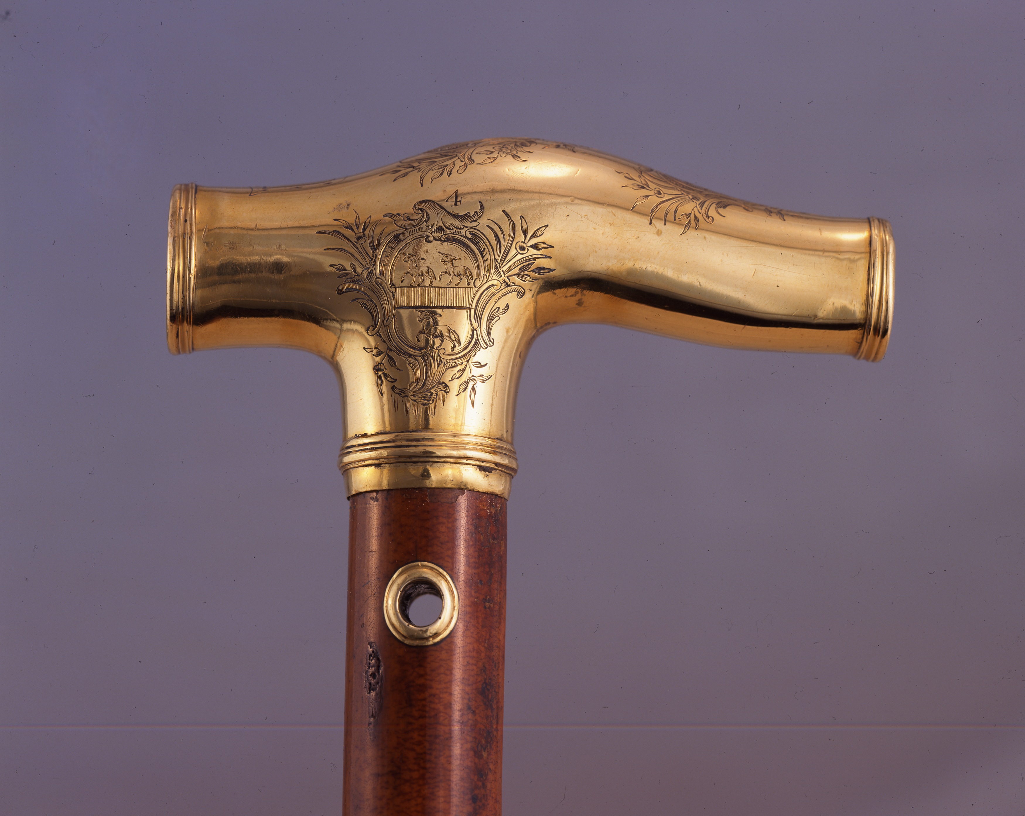 Detail of a gold cane handle, with a coat of arms.